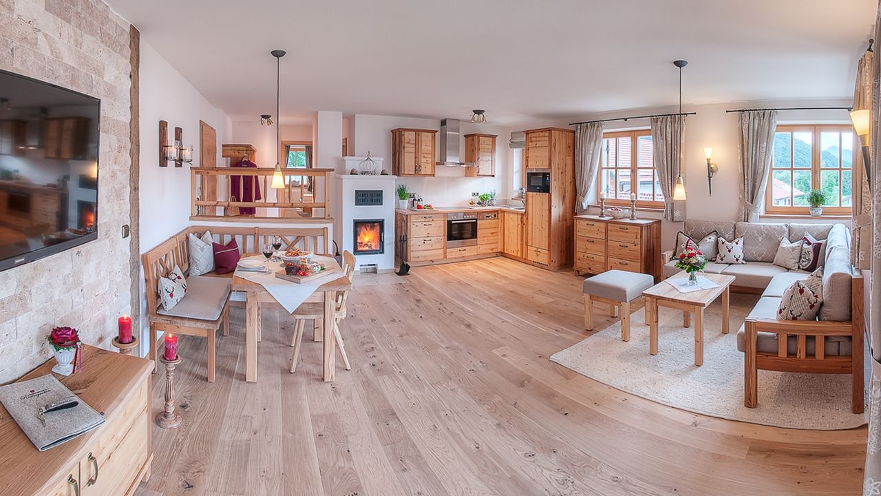 Wohnraum mit Ecksofa, Essgruppe, Kachelofen und Küche Wohnraum mit Ecksofa, Essgruppe, Kachelofen und Küche